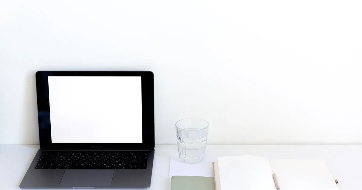 Laptop y cuaderno para evaluar un sistema de gestión empresarial