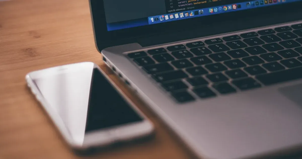Laptop con código y smartphone para el desarrollo de aplicaciones móviles